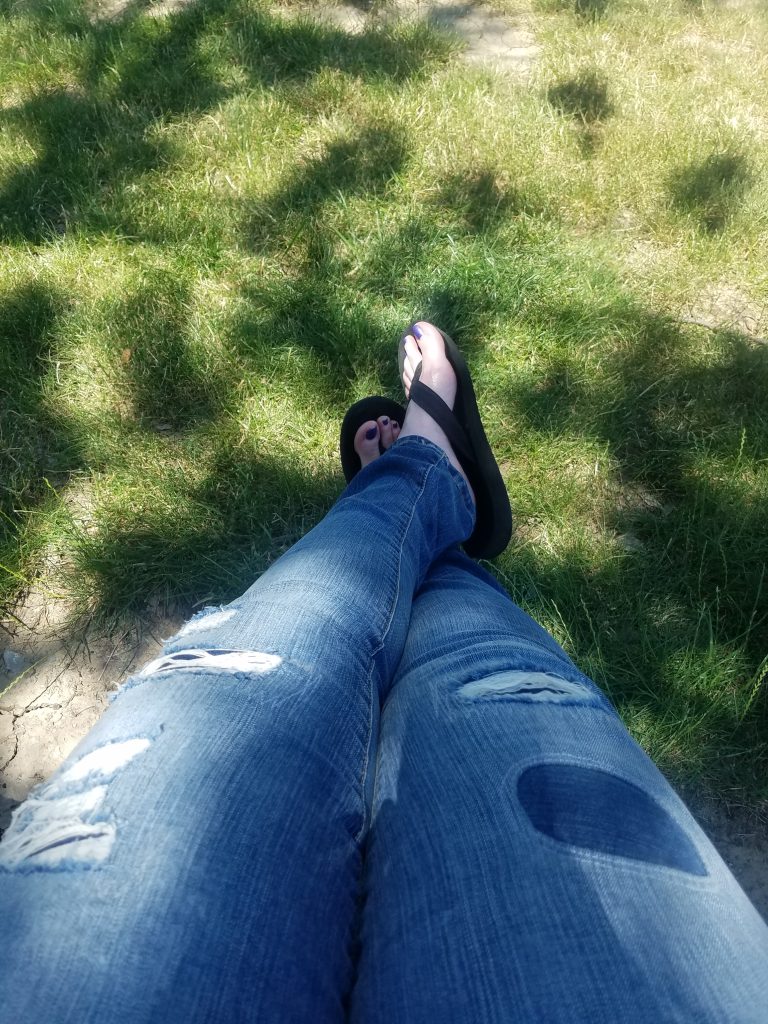 girl wearing jeans sitting in the shade at Royals game